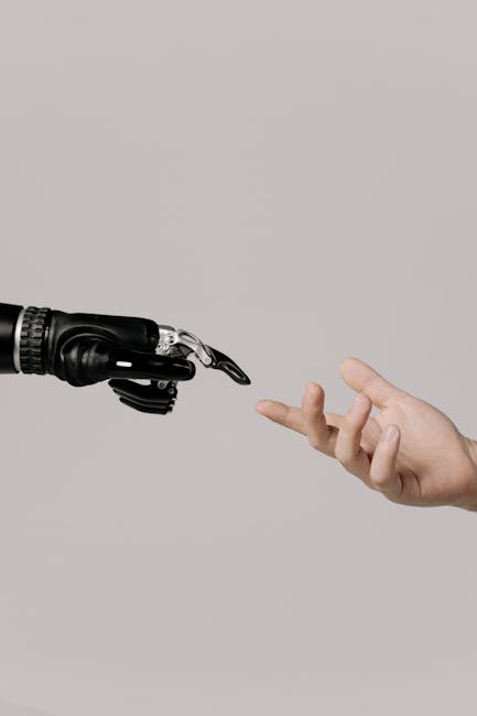 pexels-photo-6153343-6153343 A human hand reaching to touch a bionic prosthetic hand on a white background.